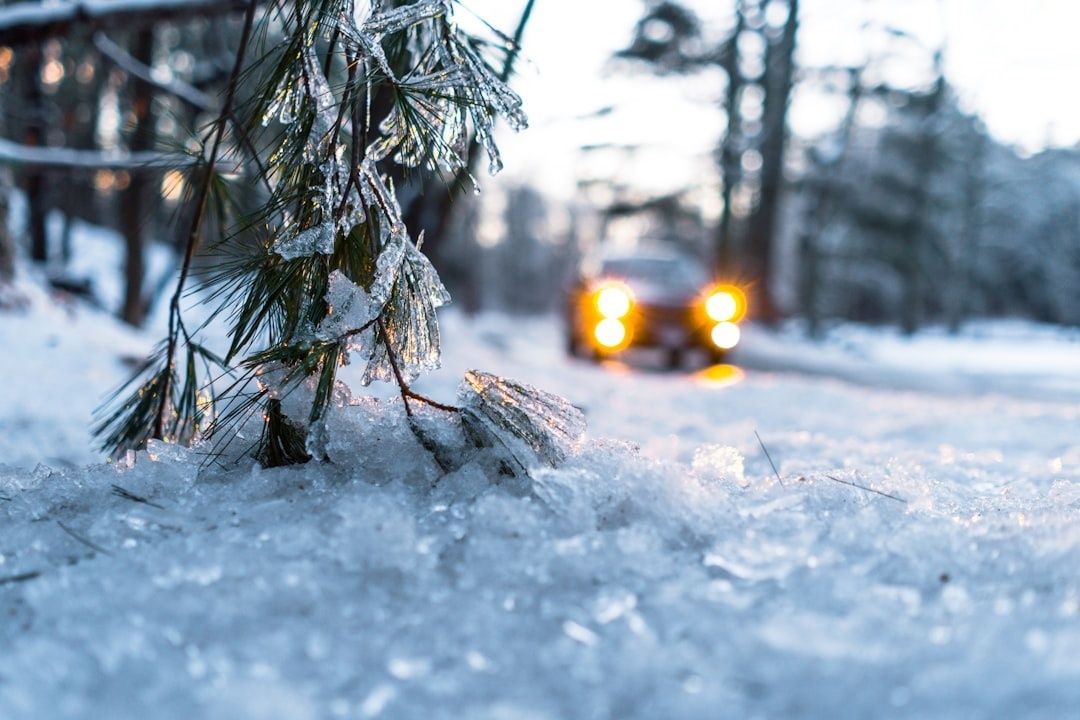 Bil med tända strålkastare på isig, snötäckt väg i vinterlandskap