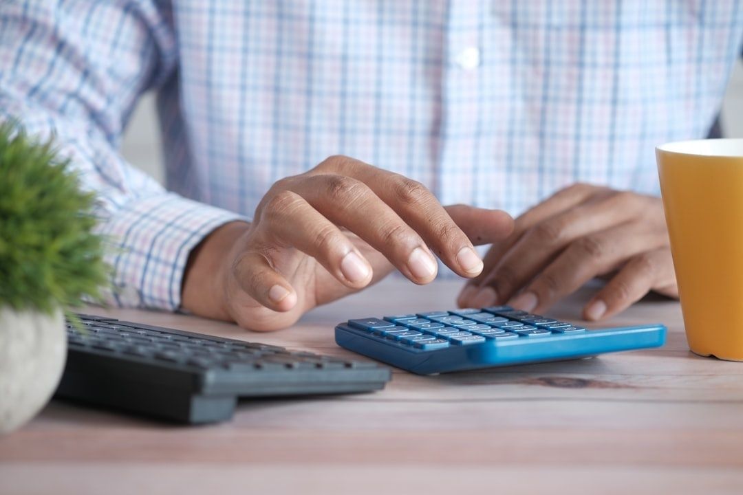 Person räknar på kalkylator vid skrivbord, relevant för bilfinansiering